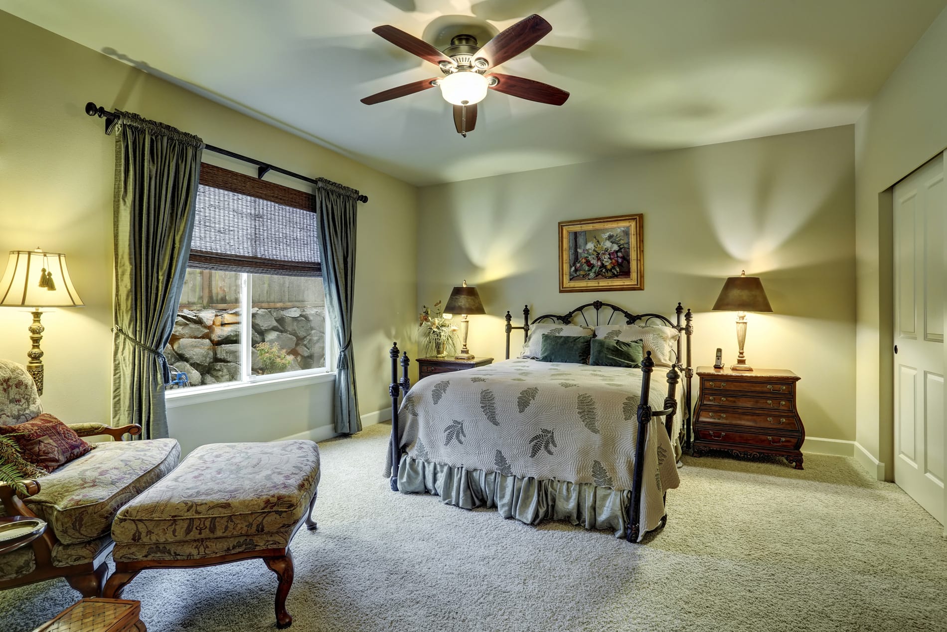 A well-appointed bedroom showcasing a bed, chair, lamp, and window, crafted by a Utah basement builder for style and function.