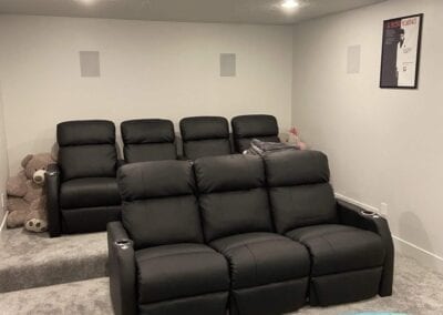 A luxurious home theater room featuring black leather recliners, designed by a Utah basement builder for ultimate comfort.