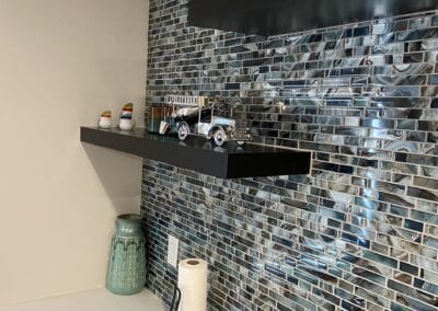 Contemporary bathroom showcasing a glass tile wall and a stylish shelf, crafted by a Utah basement builder for optimal design.