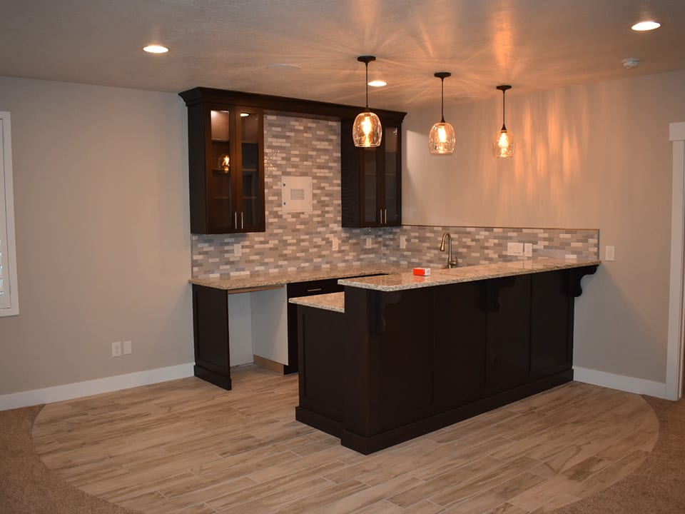 A modern kitchen featuring a bar area and stylish cabinets, designed by a Utah basement builder for optimal space utilization.