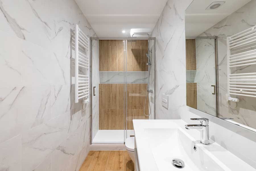 A stylish bathroom showcasing marble walls and white fixtures, crafted by a professional Utah basement builder.