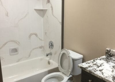 A modern bathroom layout with a toilet, tub, and sink, highlighting the expertise of a Utah basement builder.