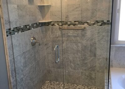 A modern shower featuring a glass door alongside a stylish bathtub, designed by a Utah basement builder.