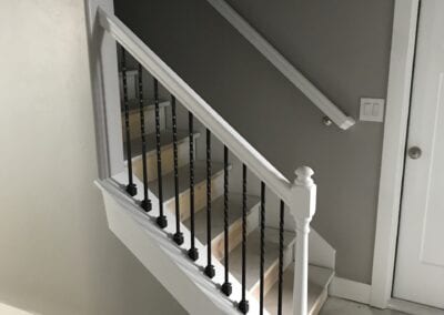 A stairway featuring white railings leads to a door, showcasing the craftsmanship of a Utah basement builder.