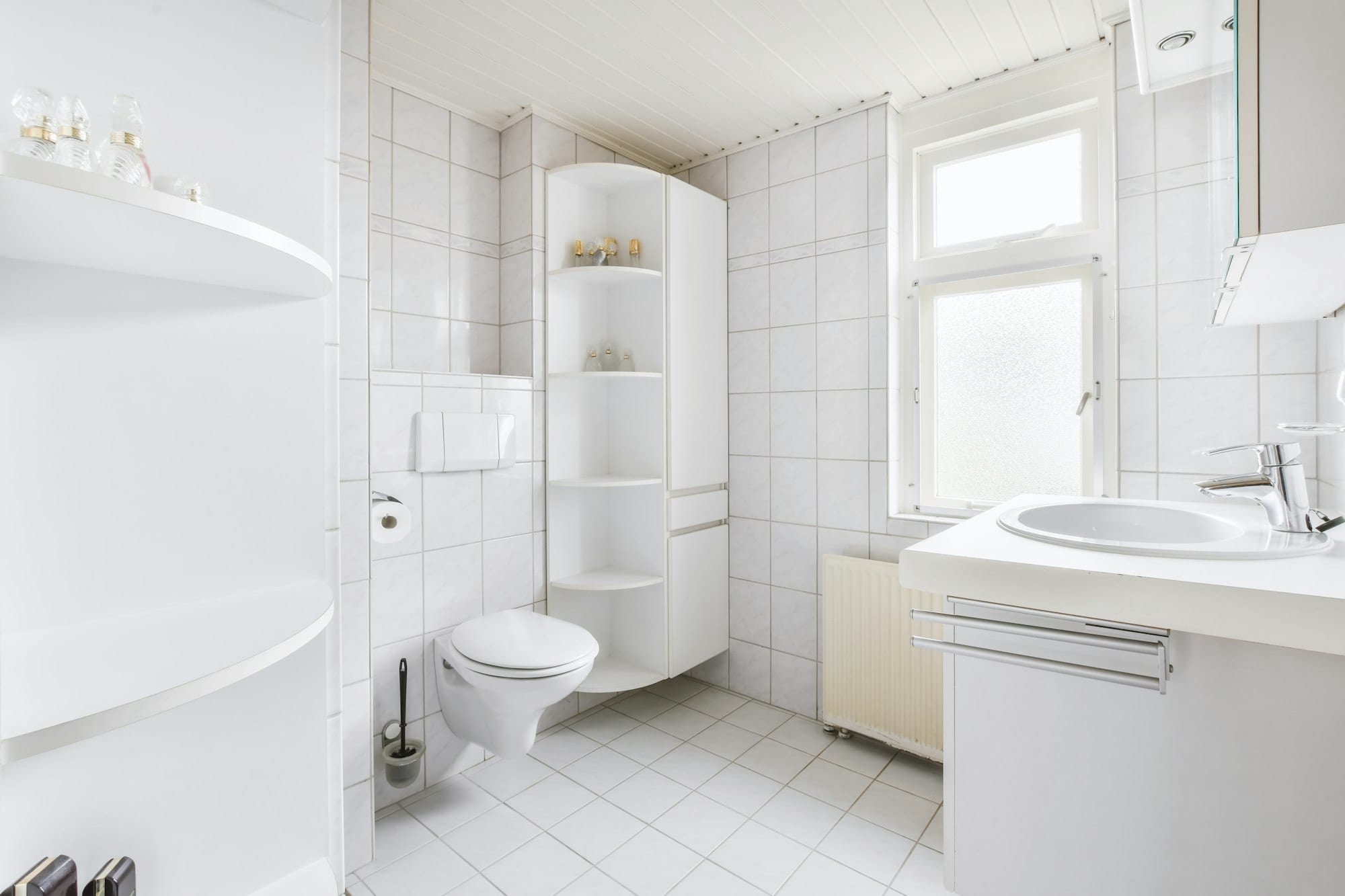 A modern white bathroom featuring a toilet, sink, and shower, designed by a Utah basement builder for optimal space utilization.