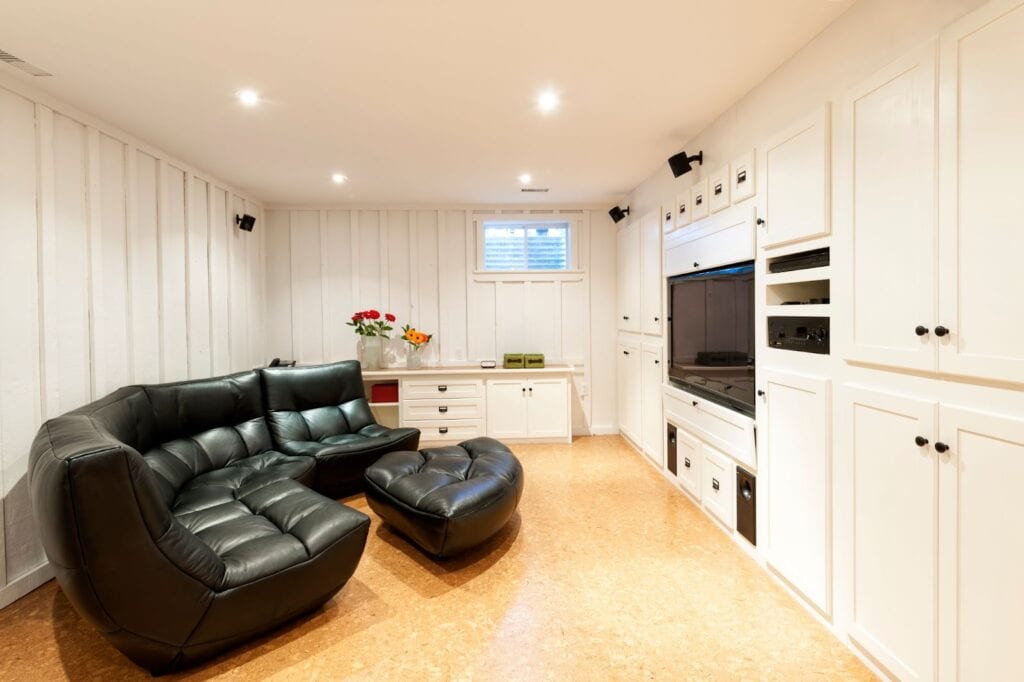 Black leather couch in room with white walls, basement flooring, contractor, subflooring