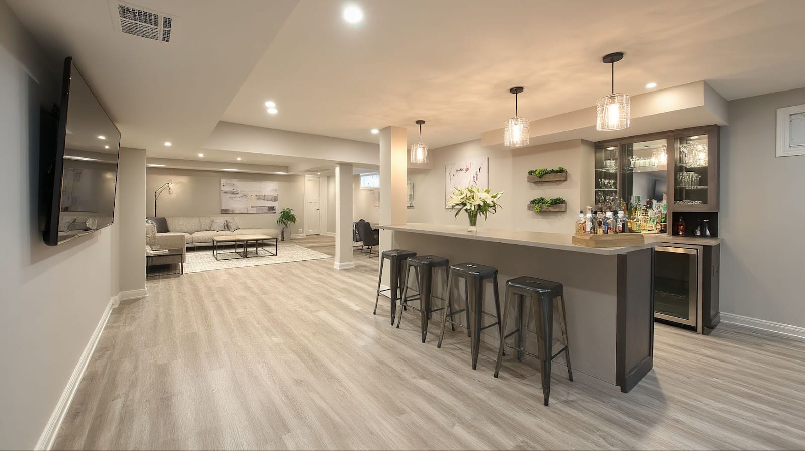 Modern basement with a bar area, seating, and a TV.